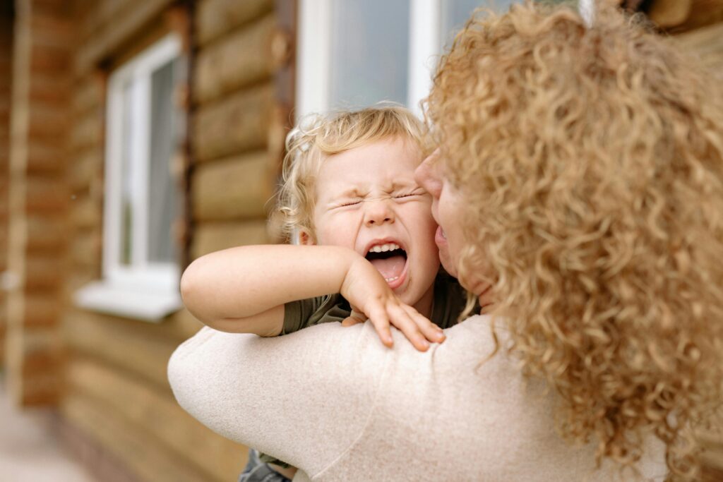 Crises, pleurs, colère : comprendre les besoins cachés de l’enfant A joyful moment of a grandmother and grandson embracing and laughing outdoors.